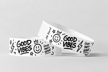 Dva bílé papírové náramky s černým potiskem ve stylu doodle